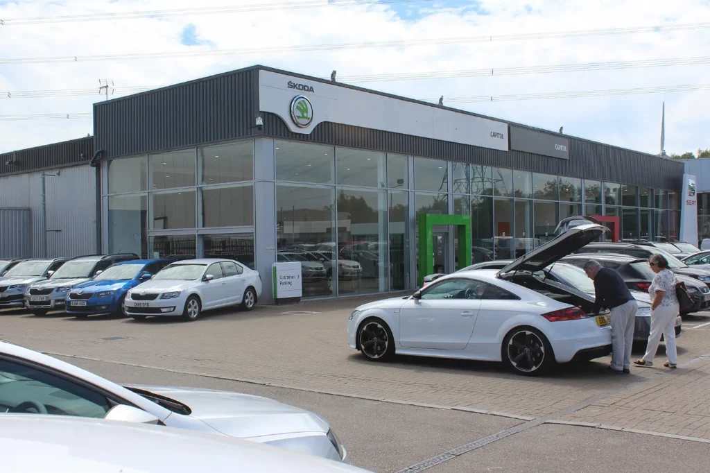 Sala de exhibición de un dealer con carros estacionados al frente, compra donde a veces el registro se atrasa