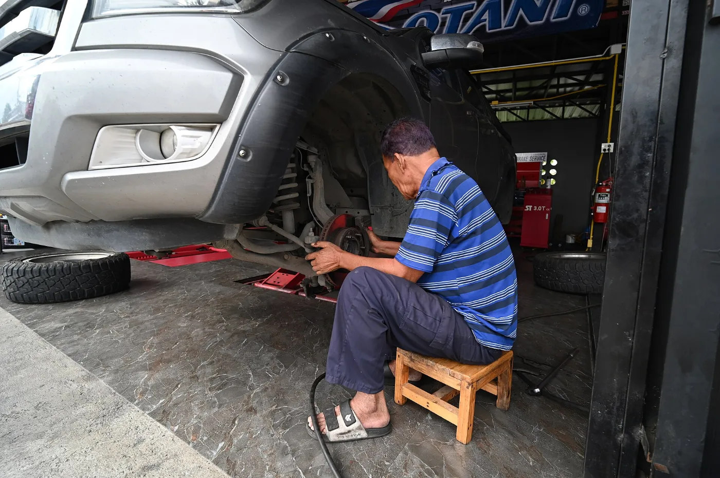 Mecánico trabajando en la llanta de un carro, reparación antes de volver a la prueba de inspección