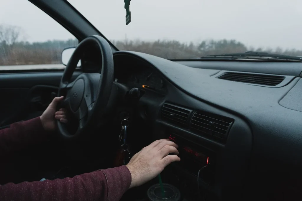 Persona dentro de su carro ajustando el tablero, lista para circular con placa temporal registrada sin seguro social