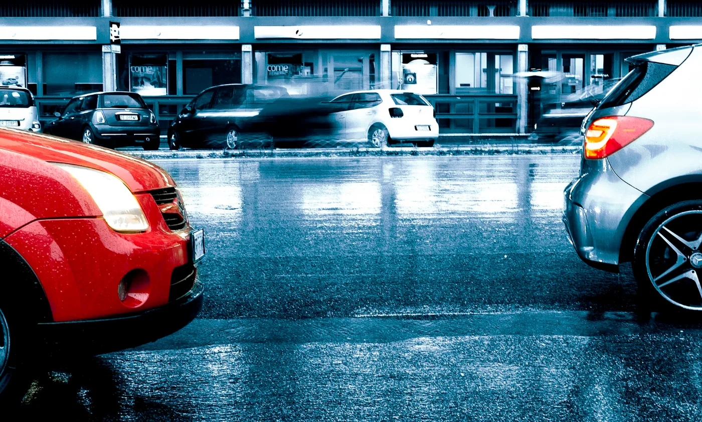 Carro circulando bajo la lluvia, con placa temporal renovada y vigente