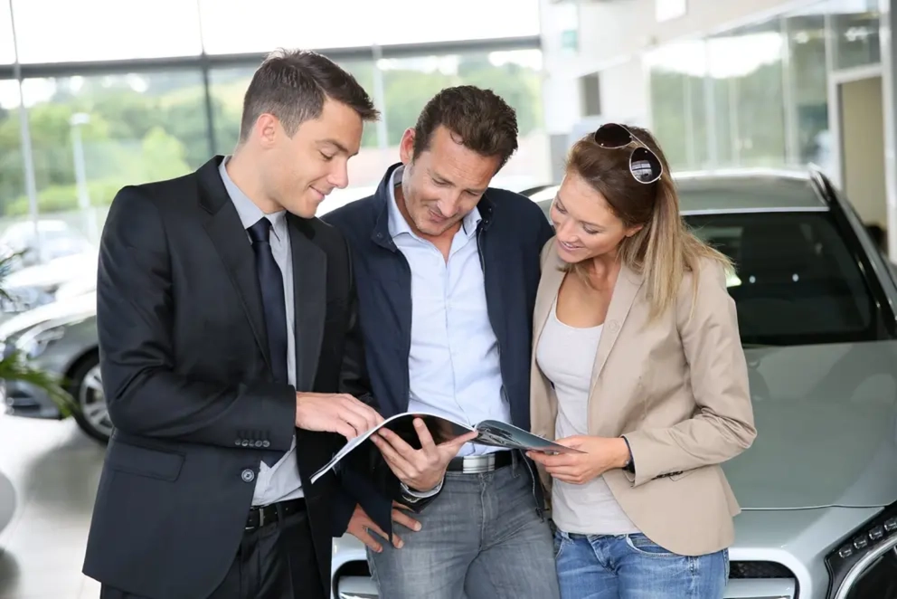 Asesor comparando opciones de aseguranza de auto con una pareja de clientes