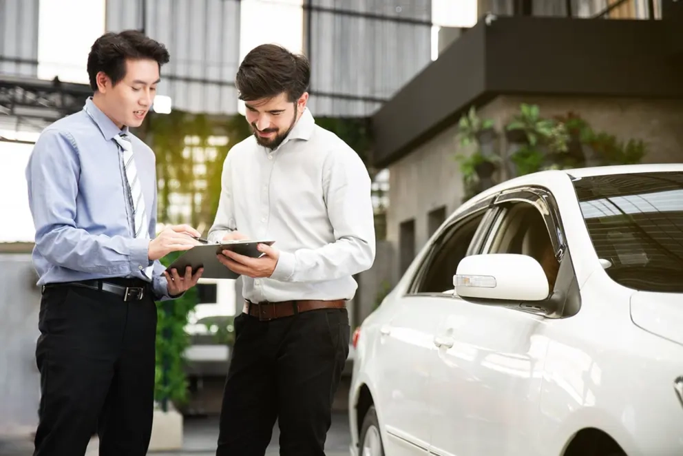 Asesor revisando los documentos del carro con un cliente antes de emitir la placa temporal